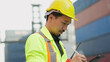 © M Stocker - Young asian Japanese foreman in hardhat and safety uniform working on tablet checking inventory cargo container at industrial yard. Foreman working at container cargo. Logistic concept