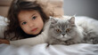 © EltaMax99 - Small Asian child lies on a bed with a cat. Kitten and baby childhood friendship. Baby and cat. Child and Kitten lying together on the bed