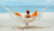 © Soloviova Liudmyla - Young woman relaxing in wicker hammock on the sandy beach on Mauritius coast and enjoying wide ocean view waves. Exotic countries vacation and mental health concept image.