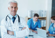 © Nicola K/peopleimages.com - Smile, crossed arms and portrait of doctor in meeting with nurses for medical research in hospital. Happy, confident and senior male surgeon in clinic office with healthcare workers for discussion.