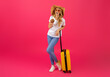 Leinwandbild Motiv Joyful Blonde Woman Traveler With Suitcase Drinking Cocktail, Pink Background