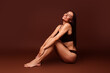 © deagreez - Full size photo no filter of attractive young woman sit floor enjoy procedure dressed stylish underwear isolated on brown color background
