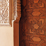 Fototapeta Tęcza - Ornamental detail of the decorative richness of the Alhambra in Granada, mixing the plasterwork with the starry geometric motifs carved in wood on a palace door.