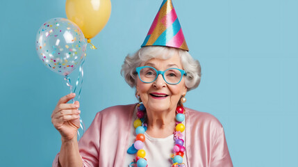 Cheerful grandmother with balloons celebrating birthday party. Happy grandma old woman wearing party hat on blue pastel background