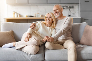 Wall Mural - Beautiful elderly caucasian couple cuddling on couch at home