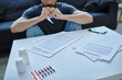cropped view of ill man sitting at table with papers and pills on it during mental breakdown