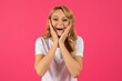 Leinwandbild Motiv Portrait Of Excited Young Blonde Woman Cupping Face, Pink Background