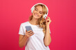 © Prostock-studio - Happy blonde woman with smartphone and headphones listening music, studio