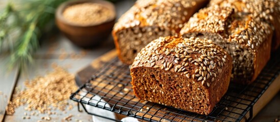 Sticker - Top-down view of homemade whole grain bread with seeds cooling on a wire rack on a wooden table, flatlay.