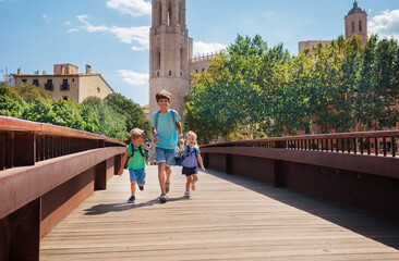 Wall Mural - Happy kids hold hands and cross the bridge in Girona, Spain