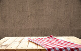 Fototapeta Tulipany - Retro background with wooden table and tablecloth over red rough wall. High quality photo