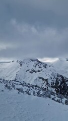 Wall Mural - Winter mountain peaks covered by fluffy snow clouds, beautiful aerial view 