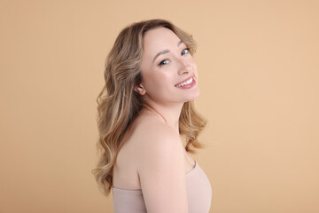 Wall Mural - Portrait of smiling woman on beige background