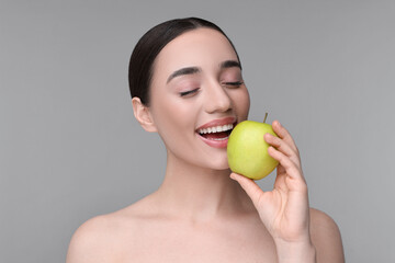 Poster - Beautiful young woman with apple on grey background