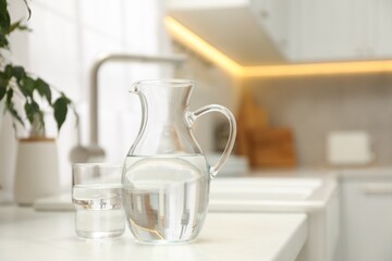 Poster - Jug and glass with clear water on white table in kitchen, space for text