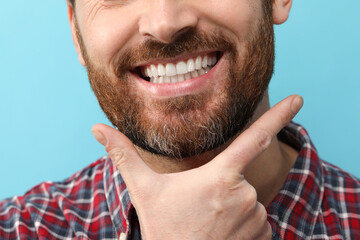 Poster - Smiling man with healthy clean teeth on light blue background, closeup