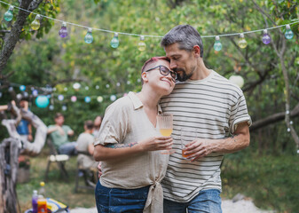 Young mature adult romantic hipster couple spending time hugging during a garden party at suumer. Love concept