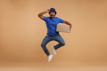 Canvas Print - Happy courier with parcel jumping on light brown background