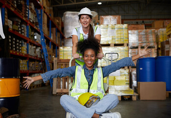 factory workers moving cart and having fun in the warehouse storage