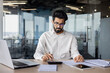 © Tetiana - Focused indian businessman working on laptop in modern office - corporate professional concept