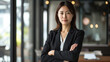 Confident businesswoman in office. Self-assured Japanese woman in a suit, arms crossed in a modern office setting