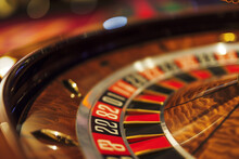 Closeup of a roulette wheel at a casino. The game consists of a ball landing on red, black, or green and people betting on numbers or colors.