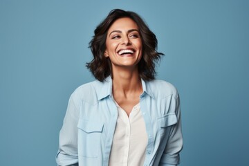 Portrait of happy young woman laughing and looking up against blue background