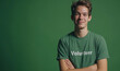Portrait of a friendly young person wearing a green volunteer tshirt against a green background