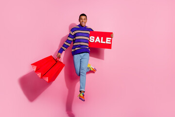 Sticker - Full length photo of excited cheerful guy dressed pullover jumping high holding bargains sale card empty space isolated pink color background