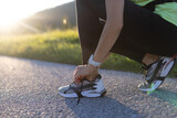 Fototapeta Las - Close-up of young woman tying her shoes before workout