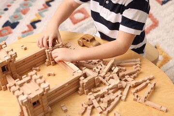 Canvas Print - Little boy playing with wooden construction set at table indoors, closeup. Child's toy