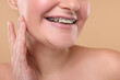 © New Africa - Smiling woman with dental braces on beige background, closeup
