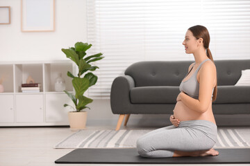 Canvas Print - Pregnant woman sitting on yoga mat at home, space for text