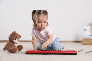 Poster - Cute little girl playing with toy piano at home