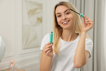 Poster - Beautiful happy woman applying mascara at home, space for text