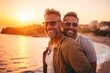 © Kate - a couple of men smile and take a selfie against the backdrop of the sea and sunset. The concept of a tourist holiday and summer mood, an unconventional couple.