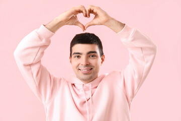 Canvas Print - Young man making heart with his hands on pink background