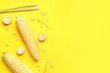 Leinwandbild Motiv Fresh corn cobs and seeds on yellow background