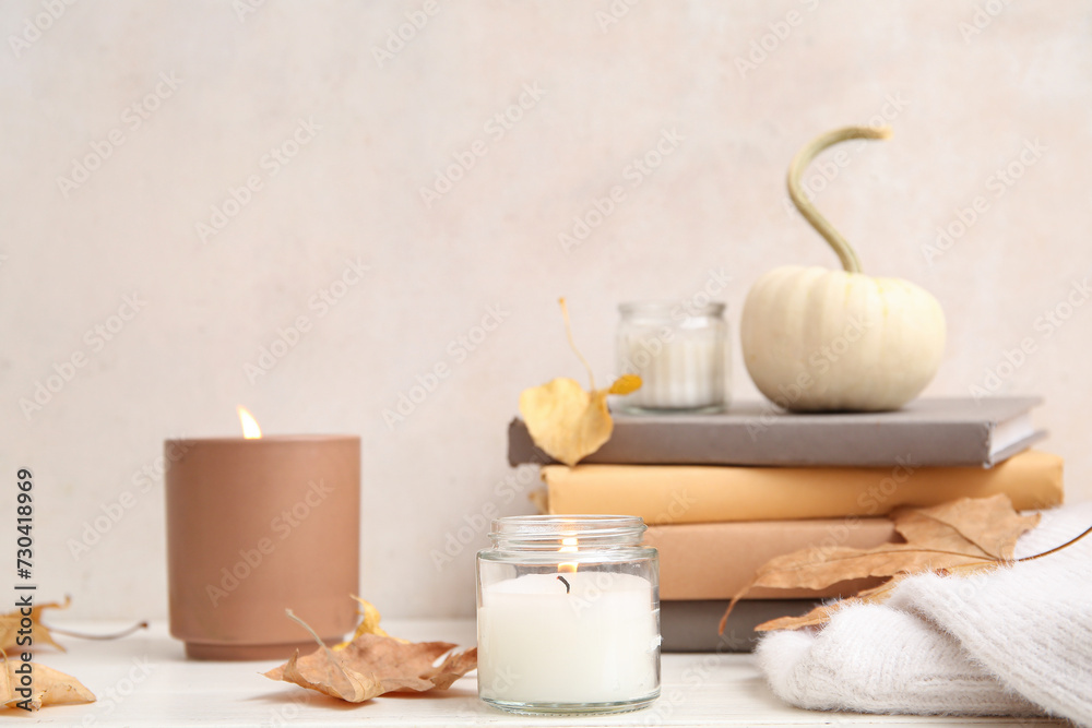 Burning candles with autumn leaves on white background
