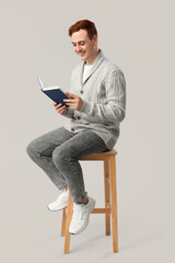 Canvas Print - Young man reading book on grey background