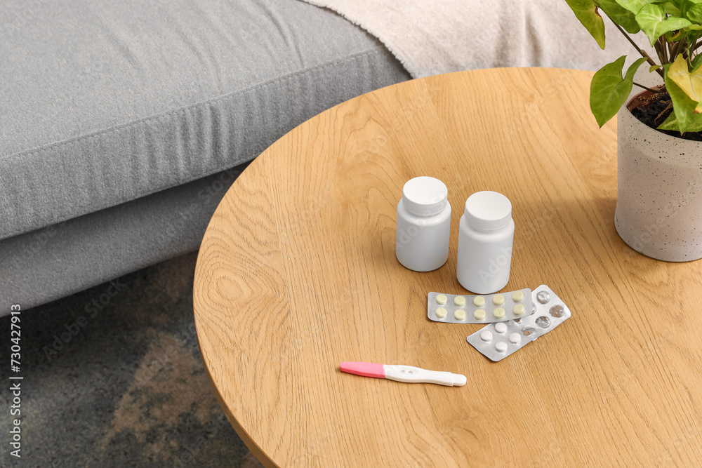 Pregnancy test with pills on table in living room, closeup