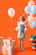 canvas print picture - Cute little girl in party hat with balloons and Birthday gifts on orange background
