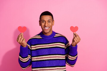 Photo of funky positive man wear striped sweater showing two small red hearts empty space isolated pink color background