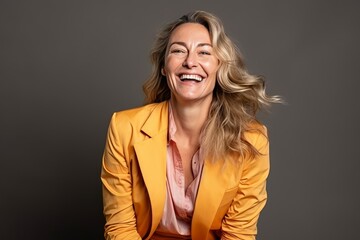 Poster - Portrait of a happy mature businesswoman laughing against grey background.