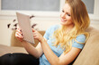 © Alex - Young Woman Reading a Digital Tablet on Sofa