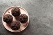 Delicious chocolate muffins on grey textured table, top view. Space for text