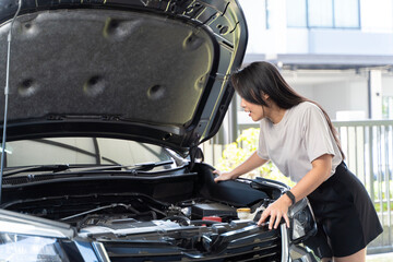 Wall Mural - A beautiful woman checking the engine in her home. She is bent over the engine, looking at it intently may be checking the oil level, changing the oil filter.