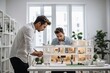 Young architect inspects and works on house plans in white office with colleagues
