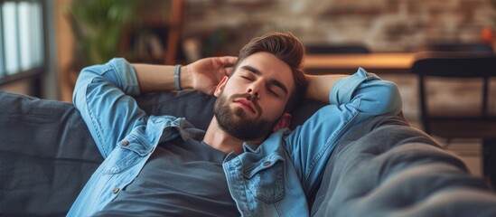 Canvas Print - Sleepy millennial guy taking a day off due to exhaustion, stress, and lack of sleep. Lazy guy resting on the couch, recharging at home. Concept of rejuvenation.