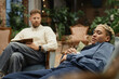 © Seventyfour - Portrait of Black adult woman lying on couch during therapy session with psychologist in blurred background